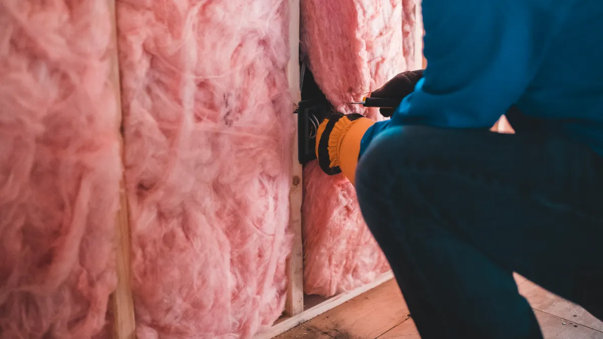Person installing pink fiberglass attic insulation