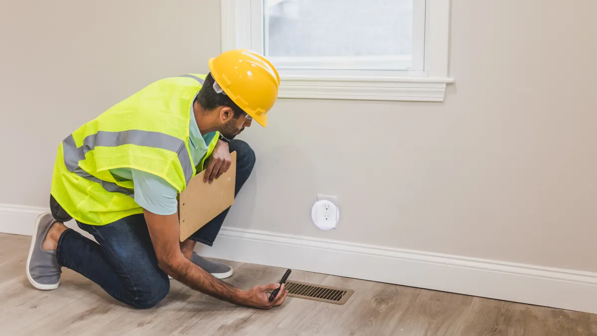 Home inspector checking a floor vent in a room