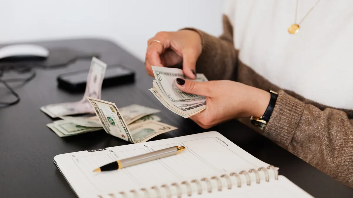 Hands counting cash over a notebook