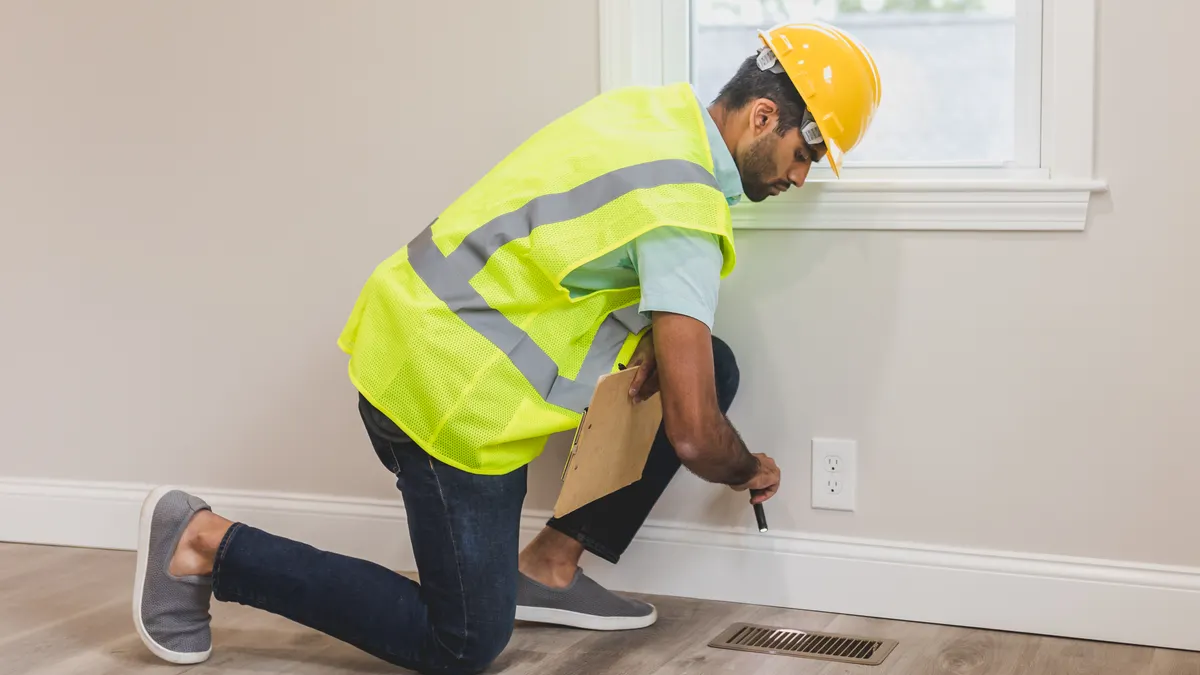 Technician inspecting a floor vent in a home